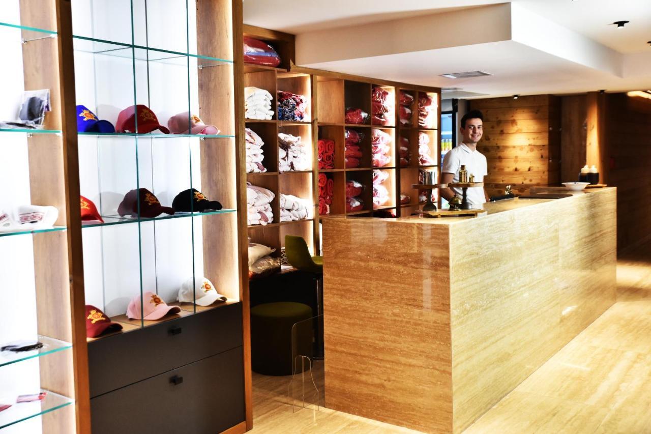 Dosso Dossi Hotels & Spa Downtown Istanbul Exterior photo The photo shows a retail space or reception area with a warm and modern design. On the left, there are shelves displaying various colorful caps, neatly arranged behind glass. The right side features a wooden counter where a staff member is standing, 