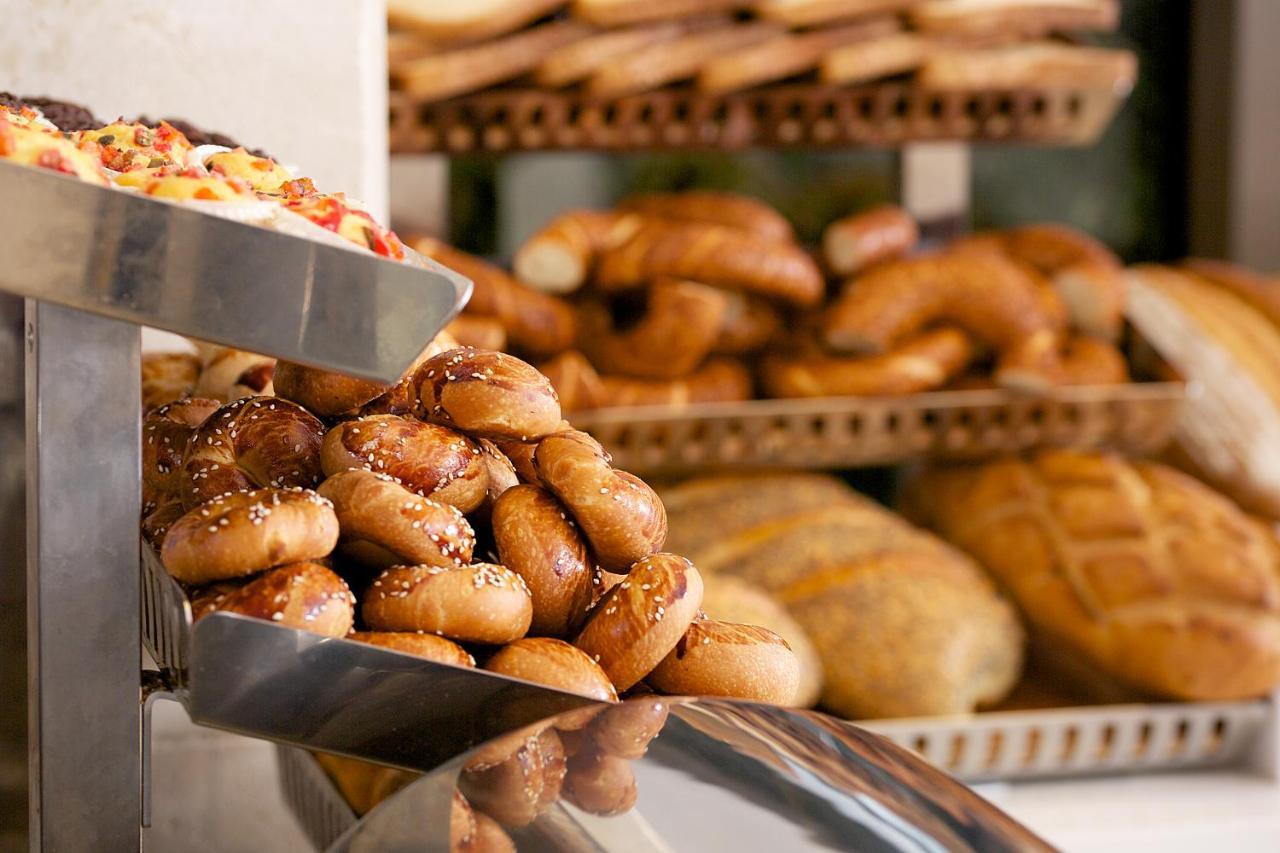 Dosso Dossi Hotels & Spa Downtown Istanbul Exterior photo The photo shows a display of various types of baked goods. In the foreground, there are small, round bread rolls topped with sesame seeds. Behind them, multiple trays are stacked with an assortment of different breads, including twisted rolls and loa