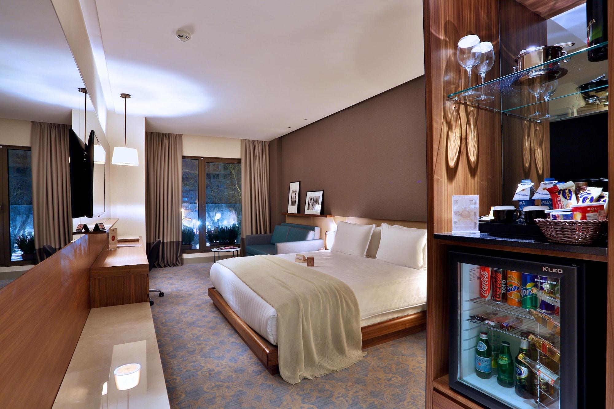 Dosso Dossi Hotels & Spa Downtown Istanbul Exterior photo The photo shows a well-decorated hotel room featuring a large bed with white linens, a bedside table, and modern furnishings. There are two windows with curtains that allow natural light to enter the space, and the walls are painted in warm, neutral 
