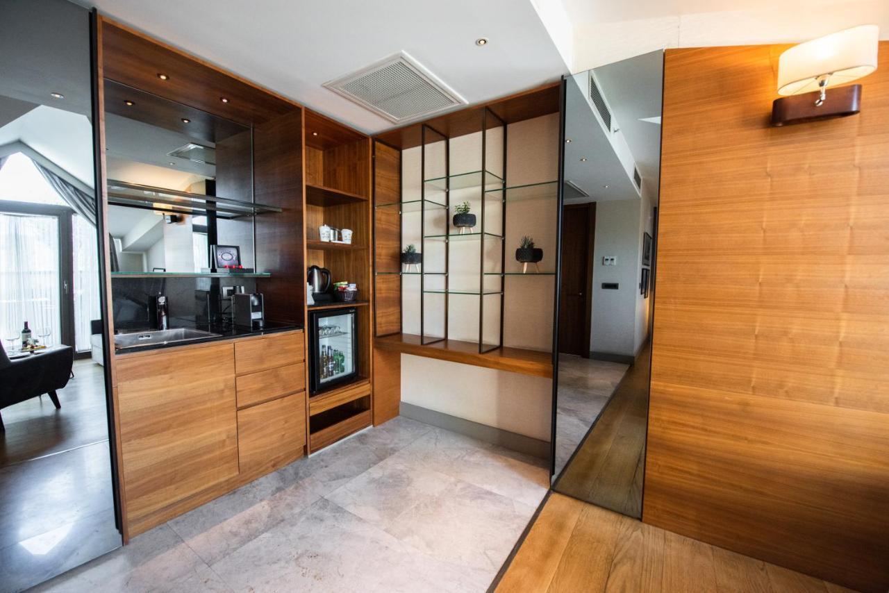 Dosso Dossi Hotels & Spa Downtown Istanbul Exterior photo The photo shows a modern interior space that features a blend of wood and glass elements. On the left side, there is a kitchenette area with wooden cabinetry and a small refrigerator, while the right side showcases a glass display unit with shelves f