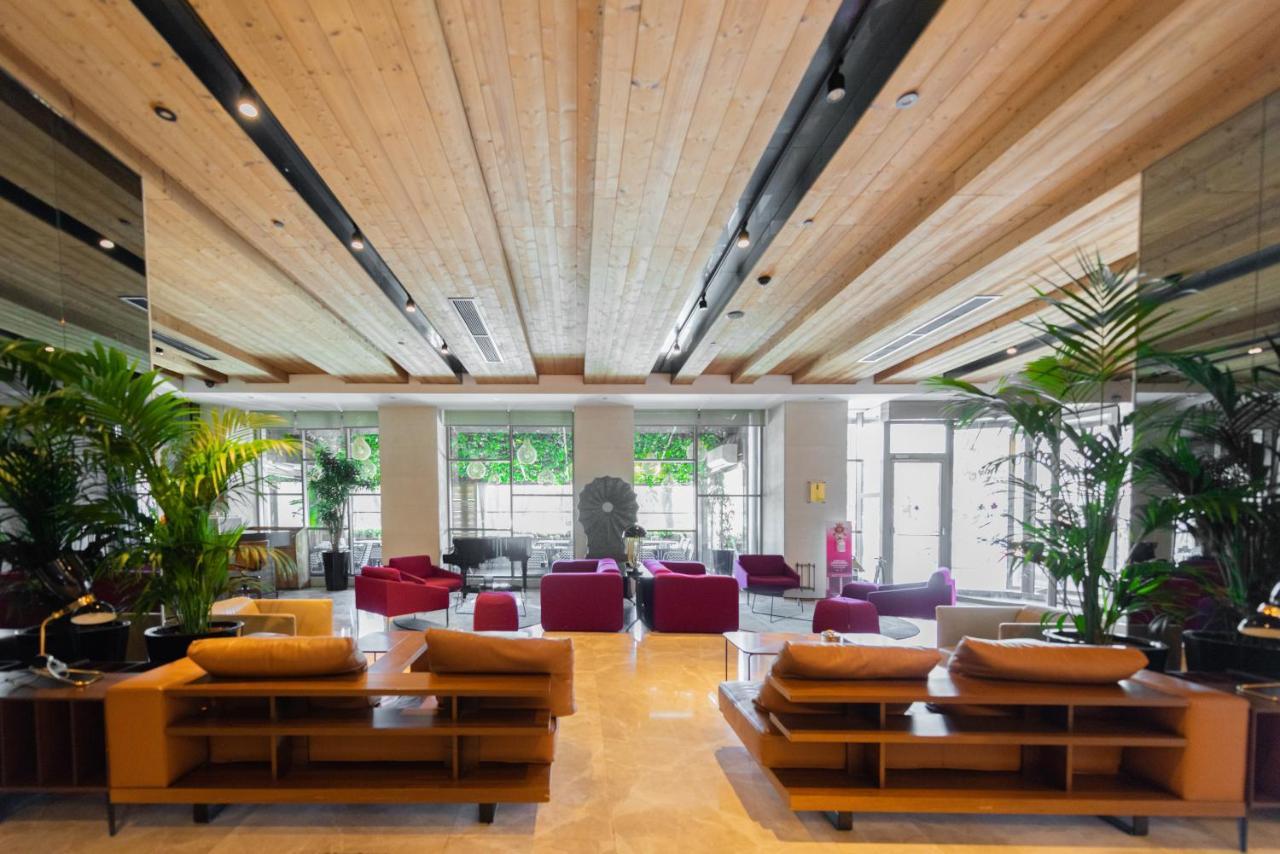 Dosso Dossi Hotels & Spa Downtown Istanbul Exterior photo The photo shows a modern and spacious lobby area. There are wooden beams on the ceiling, giving the space a warm and inviting atmosphere. The flooring appears to be light-colored stone or tile. 

In the center of the room, there are several seating a