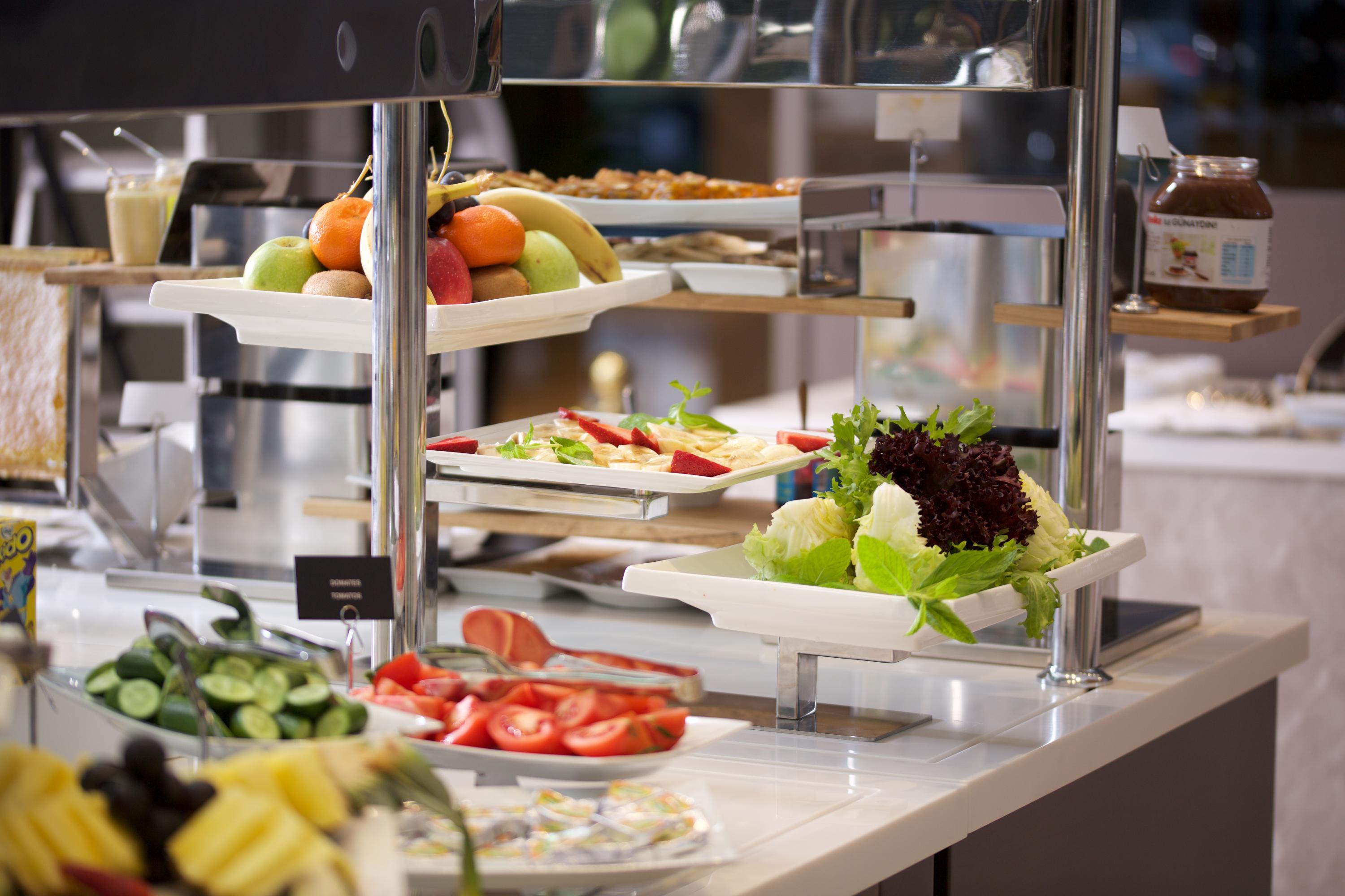Dosso Dossi Hotels & Spa Downtown Istanbul Exterior photo The photo depicts a buffet-style setup featuring a variety of fresh food items. There are several trays with colorful fruits, including apples and bananas, positioned on one side. In front, there are plates with vegetables, like sliced tomatoes and l