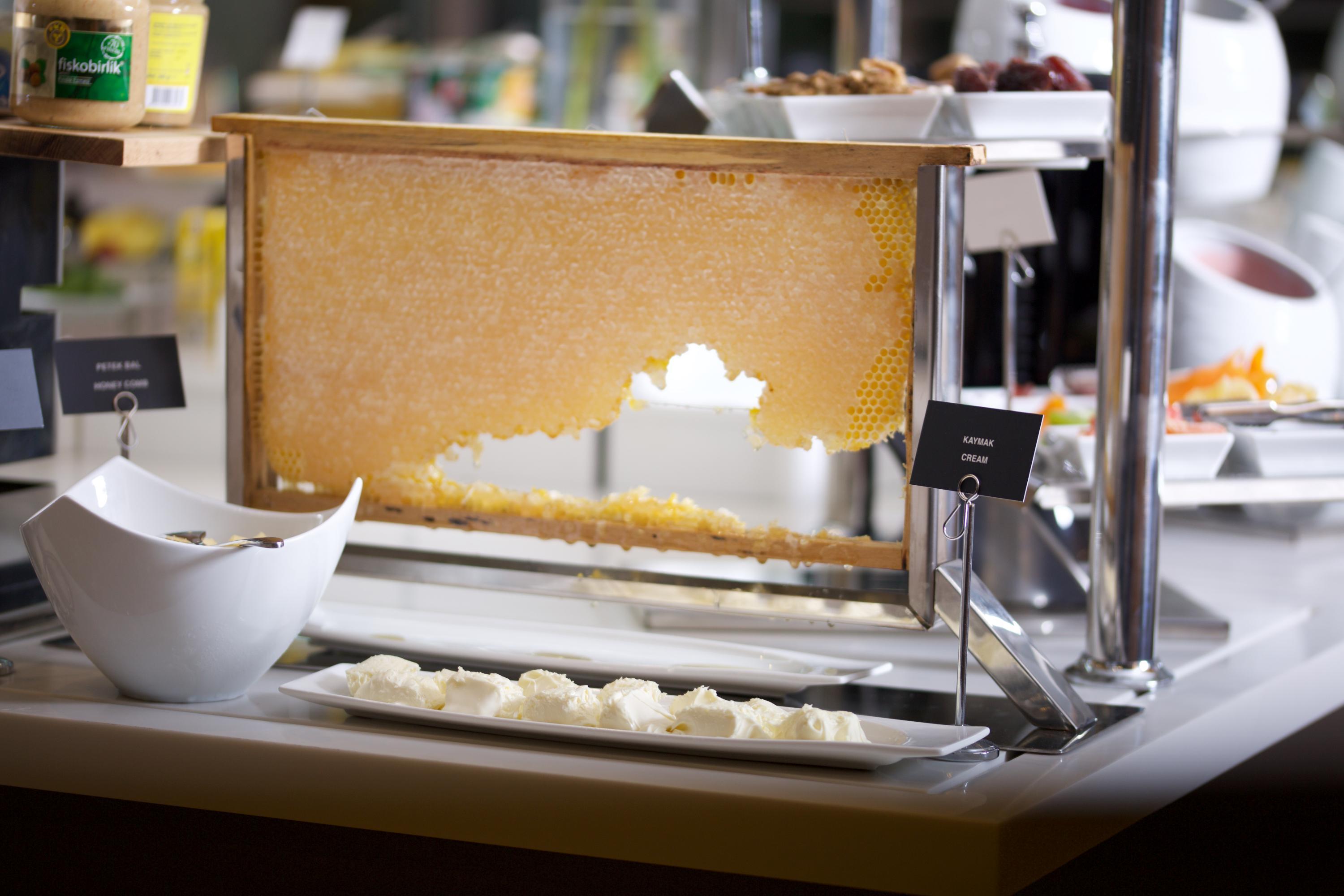 Dosso Dossi Hotels & Spa Downtown Istanbul Exterior photo The photo shows a buffet setup featuring a large piece of honeycomb displayed in a frame, from which honey can be extracted. Below the honeycomb, there is a white dish containing small portions of what appears to be a creamy substance, likely a dairy
