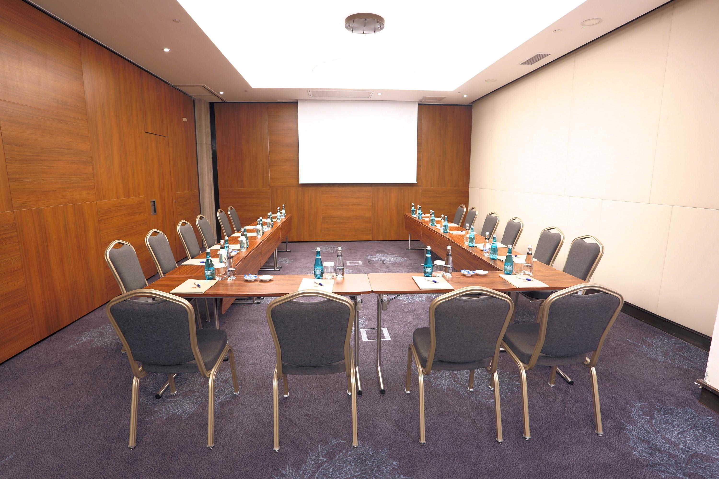 Dosso Dossi Hotels & Spa Downtown Istanbul Exterior photo The photo shows a conference room setup. There are several rectangular tables arranged in a U-shape, surrounded by chairs. Each table has a water bottle and a notepad placed on it, suggesting it's intended for a meeting or presentation. The walls are