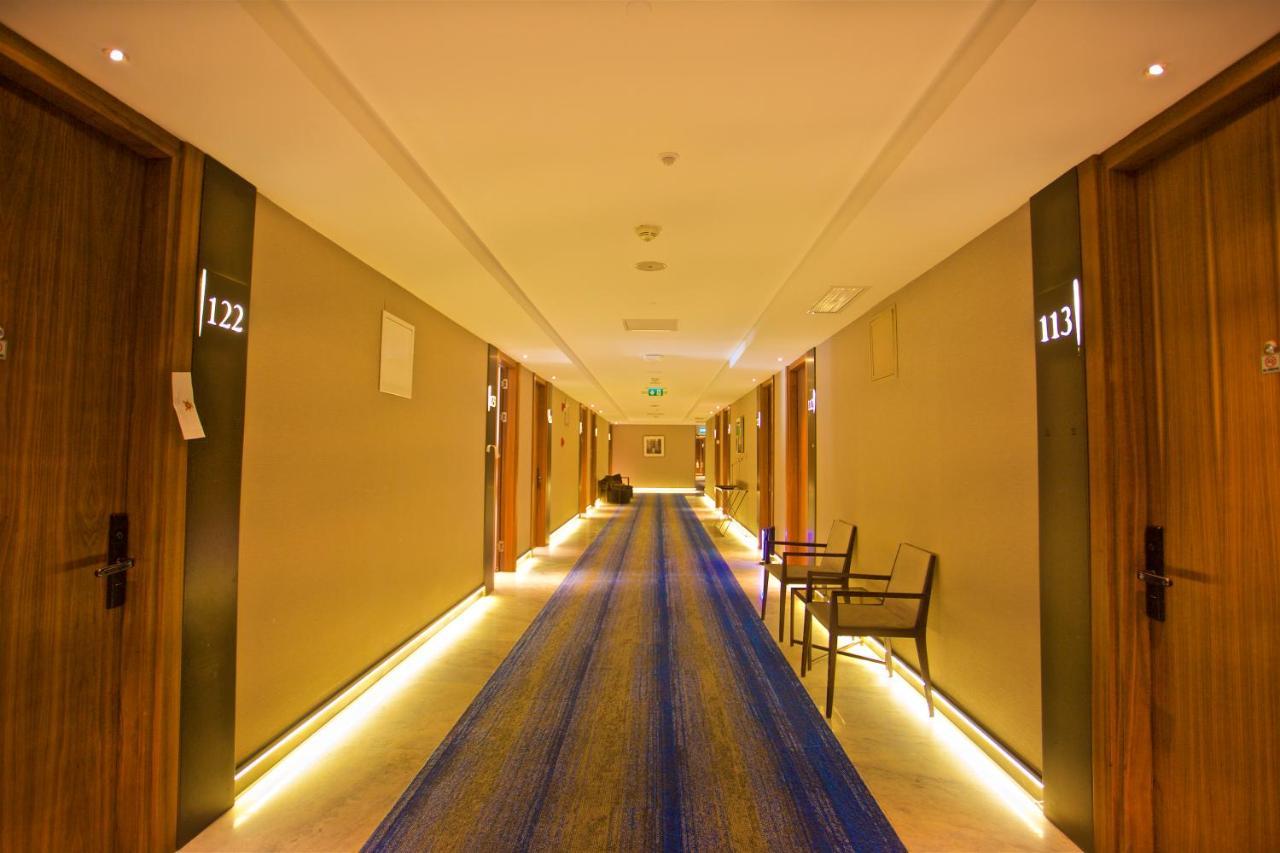 Dosso Dossi Hotels & Spa Downtown Istanbul Exterior photo The photo shows a hotel corridor with several wooden doors on either side. Each door is numbered, with numbers visible for rooms 113 and 122. The hallway features a long blue rug running down the center and has soft lighting along the sides, creating