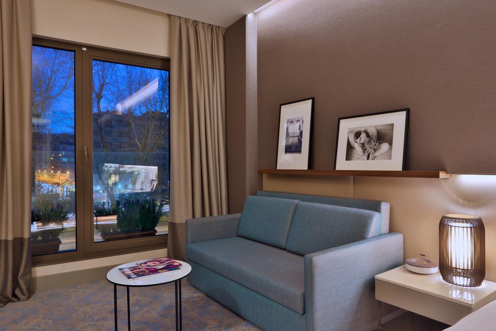 Dosso Dossi Hotels & Spa Downtown Istanbul Exterior photo The photo shows a modern and cozy interior of a room. There is a light blue sofa positioned against a wall, accompanied by a round coffee table with a magazine on top. Two black-and-white framed photographs are hanging on the wall above the sofa. Lar
