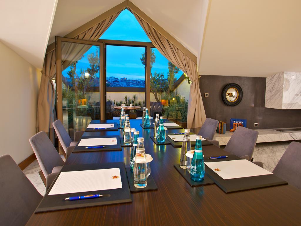 Dosso Dossi Hotels & Spa Downtown Istanbul Exterior photo The photo shows a conference room setup. There is a long wooden table with several chairs arranged around it. On the table, there are notebooks or notepads, pens, and bottles of water, all placed neatly. The room features large windows with curtains,