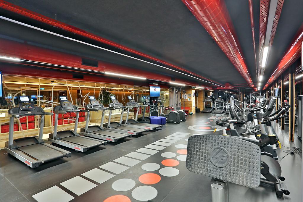 Dosso Dossi Hotels & Spa Downtown Istanbul Exterior photo The photo shows a modern fitness gym featuring various exercise equipment. On one side, there are several treadmills lined up, facing a screen, likely for entertainment or workout tracking. The flooring has a unique design with colorful circles, and 