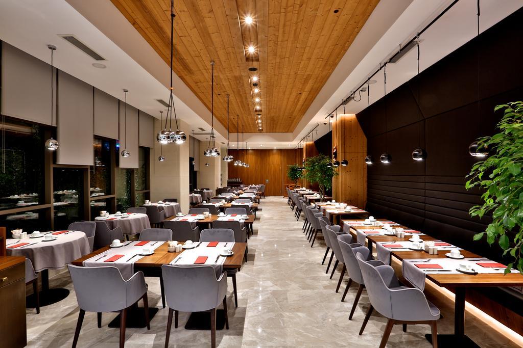 Dosso Dossi Hotels & Spa Downtown Istanbul Exterior photo The photo depicts a modern restaurant interior. The space features a combination of wooden and polished surfaces, with a prominent wooden ceiling. 

Tables are set with white tablecloths and neatly arranged dishware, indicating a refined dining exper